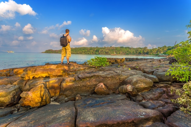 Hombre con mochila en una bahía tropical