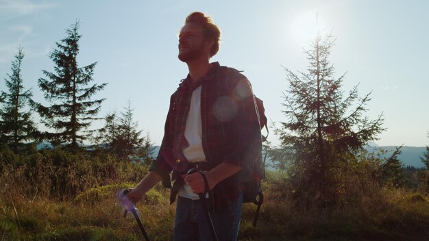 Un hombre con una mochila camina por un bosque con árboles al fondo.