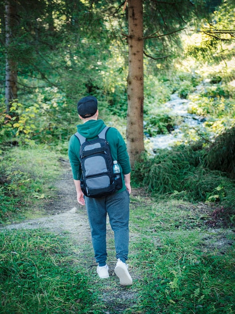 Un hombre con mochila camina en el bosque de otoño. Senderismo solo por los senderos del bosque otoñal. Concepto de viaje.