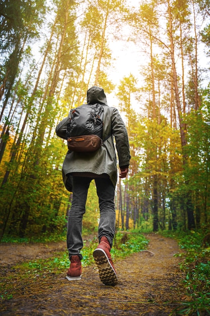 Foto un hombre con mochila camina en el increíble bosque de otoño.