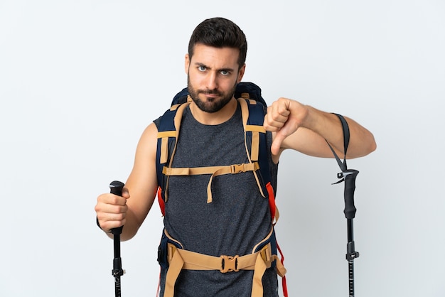 Hombre con una mochila grande mostrando el pulgar hacia abajo signo