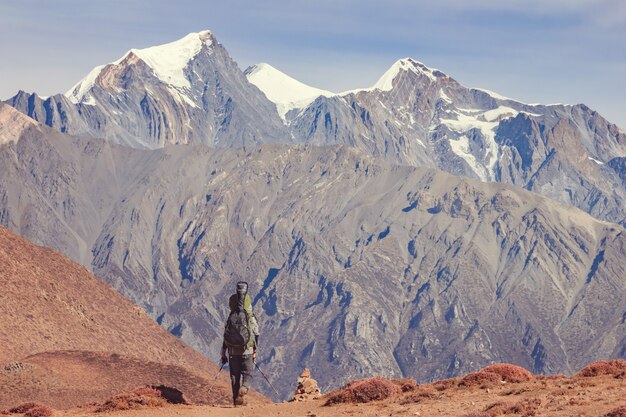 Un hombre con una mochila y una guitarra va de camino a las montañas de Nepal. Vista trasera.