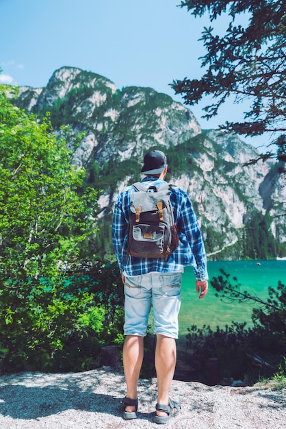Hombre con mochila mirando el lago en las montañas dolomitas