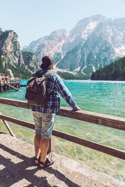 Hombre con mochila de pie mirando el lago en las montañas