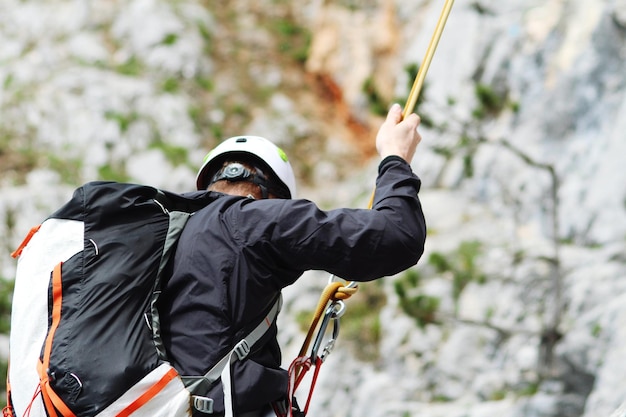 Hombre con mochila en rappel en la montaña