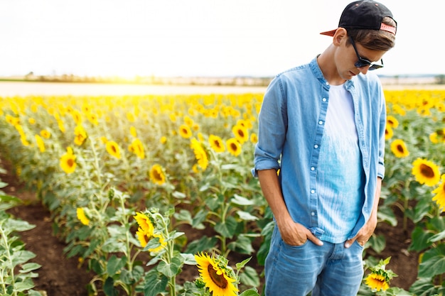 Hombre de moda con gafas de sol en el campo de girasol