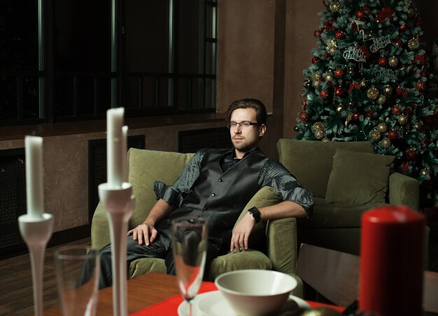 Hombre de moda en un interior moderno de lujo, tiempo de Navidad.