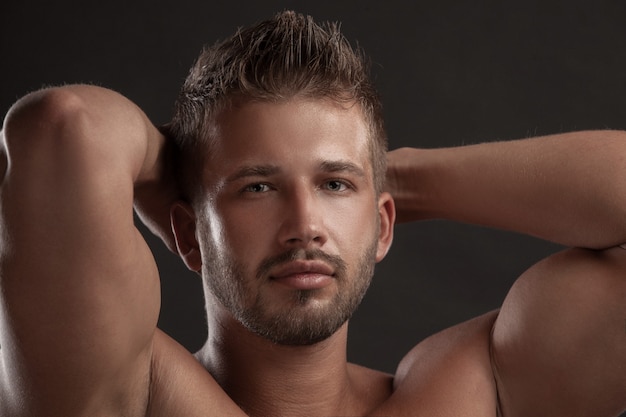 Hombre modelo con el pecho abierto sobre un fondo oscuro, cuerpo musculoso de un hombre joven en jeans. Filmada en un estudio.