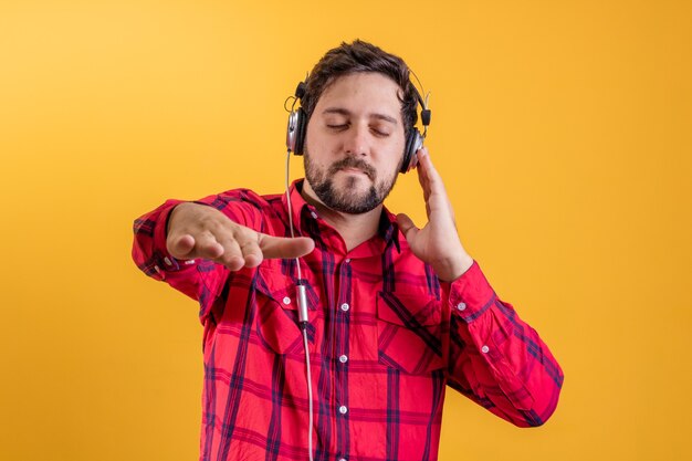 Hombre moderno guapo escuchando música en auriculares en amarillo