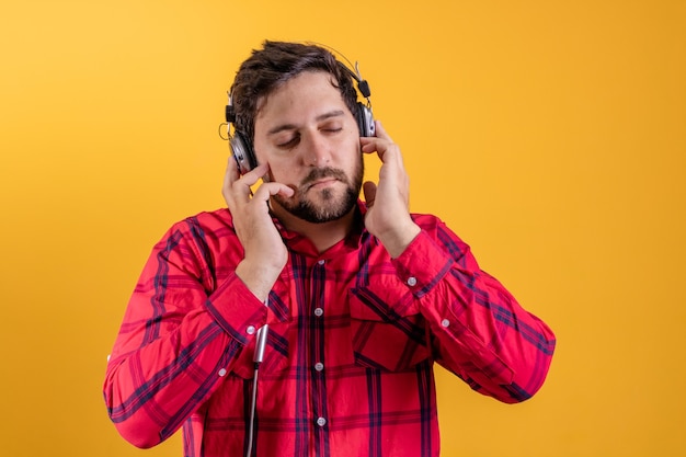 Hombre moderno guapo escuchando música en auriculares en amarillo