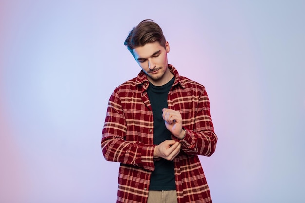 El hombre moderno, guapo, joven e inconformista con estilo, vestido con ropa elegante, se pone una camisa y se abotona la manga