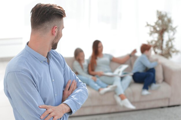 Hombre moderno parado en su sala de estar y mirando su foto familiar con espacio para copiar