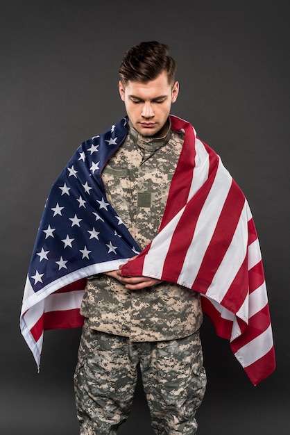 Hombre molesto en uniforme militar con bandera americana aislado en gris