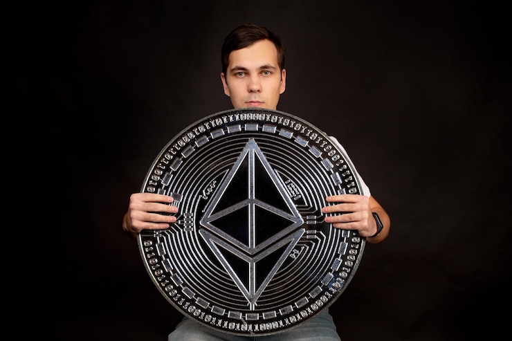 Foto un hombre con una moneda en sus manos ethereum classic se encuentra en el fondo.