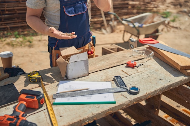 Hombre con un mono de pie en una mesa de madera con diversas herramientas