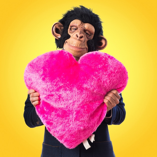 Foto hombre del mono que sostiene un corazón grande en fondo colorido