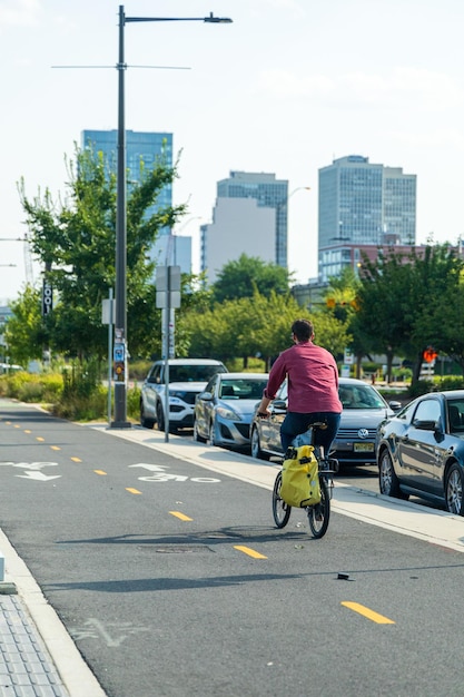 Un hombre monta una bicicleta por una calle con coches estacionados a lo largo del lado