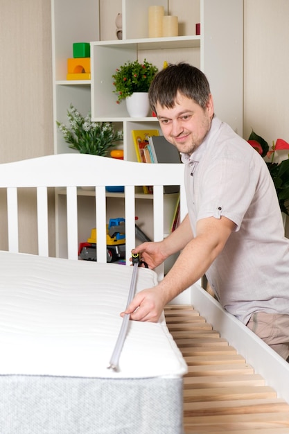 Un hombre monta una cama mide la longitud con una cinta métrica