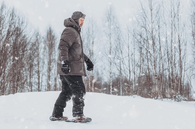 Un hombre monta un patín de nieve en un parque de invierno, un estilo de vida deportivo saludable, descansa y camina en la naturaleza en el bosque de invierno