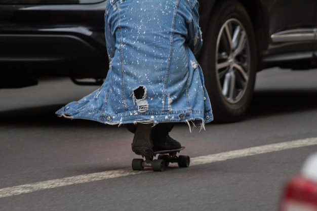 El hombre monta una patineta sentado en una franja divisoria en una calle de la ciudad