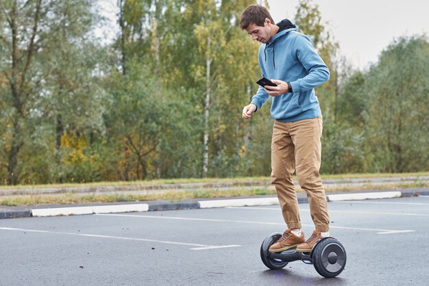 Hombre montado en el hoverboard y con smartphone