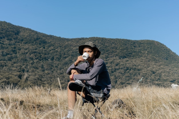 Un hombre en las montañas bebiendo de una taza.