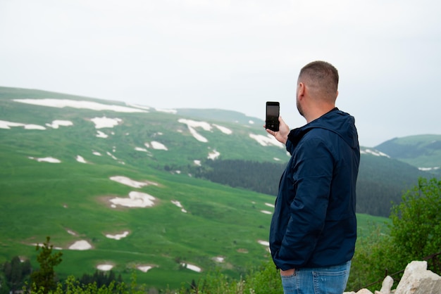 Un hombre en las montañas con un teléfono. Vacaciones.