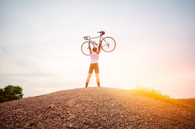 Un hombre montando bicicleta deportiva vintage para hacer ejercicio por la noche. Un hombre levantando una bicicleta en el ambiente nocturno. Un hombre anda en bicicleta por la montaña.