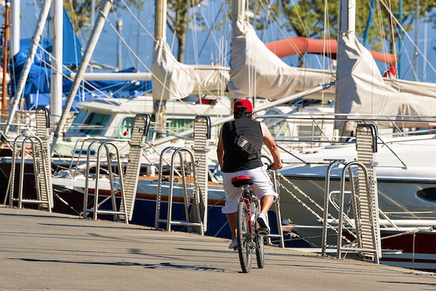 Hombre montando una bicicleta en el terraplén de la Marina en el lago de Ginebra en Lausana, pueblo pesquero de Ouchy, Suiza