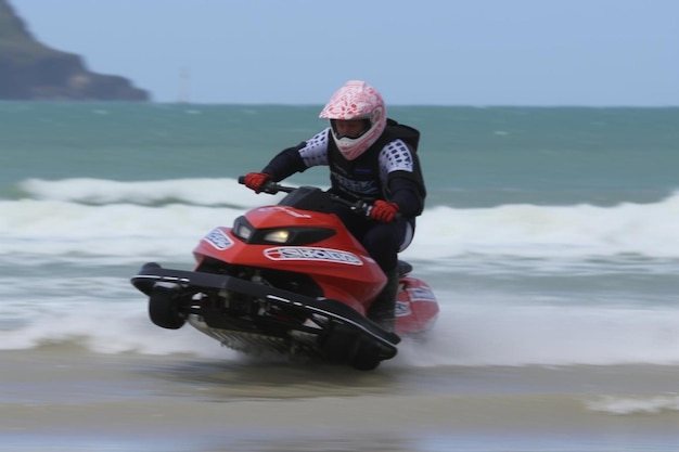 Foto un hombre montando una moto acuática en la cima de una playa de arena