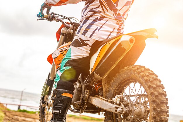 Hombre montando un motocross en un traje protector en el barro