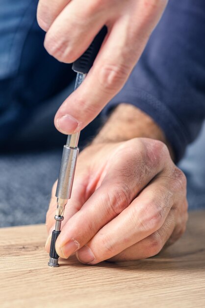 Hombre montando muebles en casa a mano con un destornillador