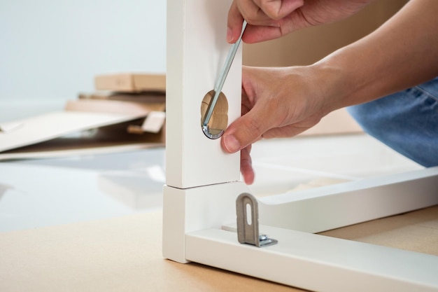 Hombre montando muebles de silla blanca en casa