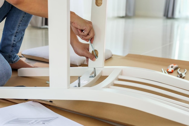 Hombre montando muebles de silla blanca en casa