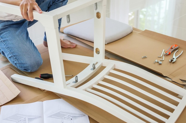 Hombre montando muebles de silla blanca en casa