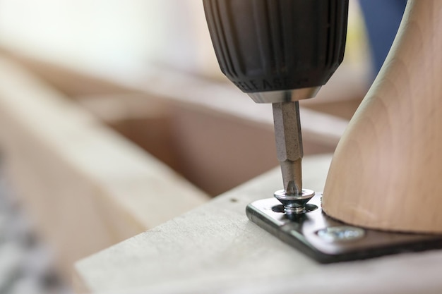 Hombre montando muebles de sofá en casa con destornillador inalámbrico