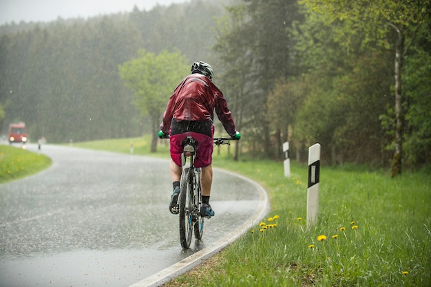 Hombre montando su bicicleta por una colina bajo la lluvia torrencial