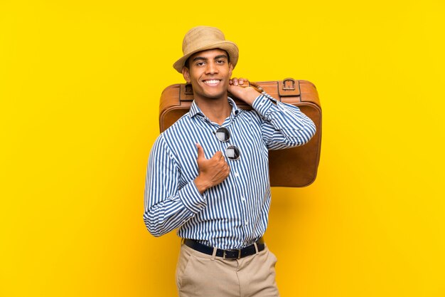 Hombre morena sosteniendo un maletín vintage con los pulgares para arriba