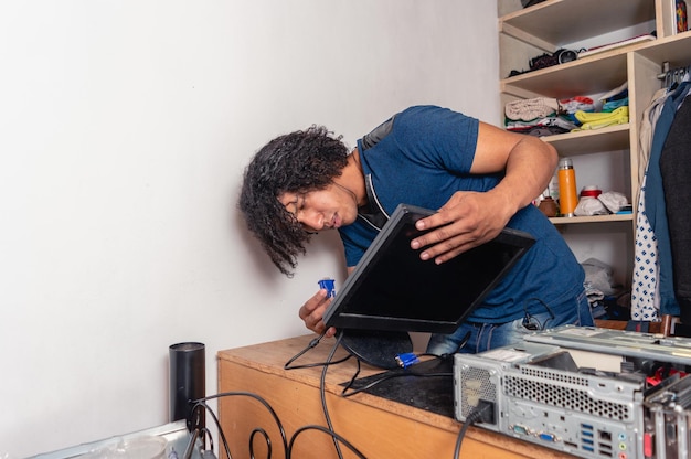 Hombre moreno en casa instalando cable de monitor de computadora