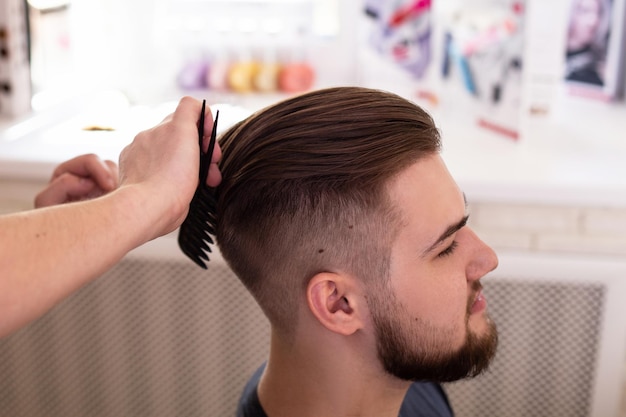 Hombre moreno con corte de pelo elegante en el fondo de la barbería