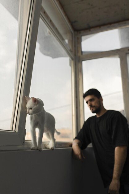 Hombre moreno con gracioso gato blanco amistad entre hombre y gato