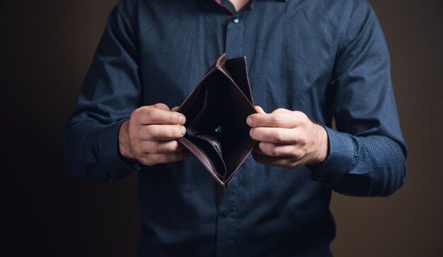 Foto hombre mostrando billetera vacía sobre superficie marrón