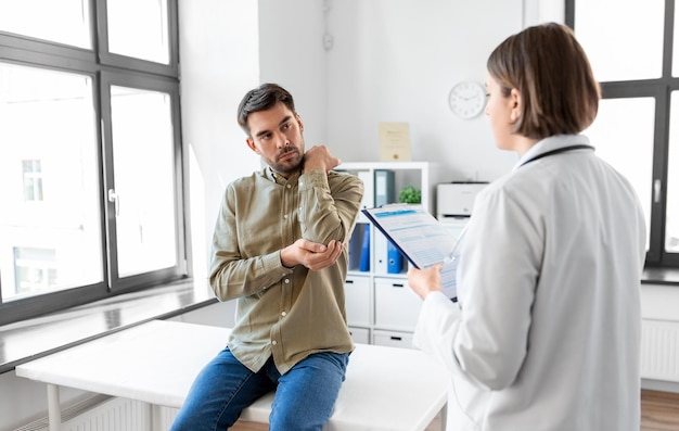 hombre mostrando el brazo dolorido al médico en el hospital