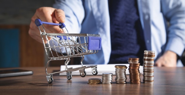 Hombre mostrando carrito de compras con monedas