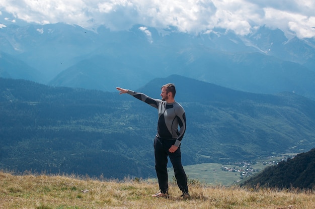 Hombre mostrando dirección con su mano y de pie en las montañas