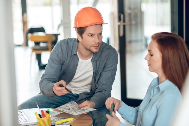 Hombre mostrando plan de construcción a mujer seria