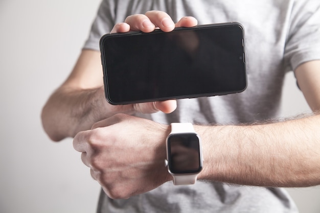 Foto hombre mostrando reloj y teléfono inteligente. estilo de vida. tecnología