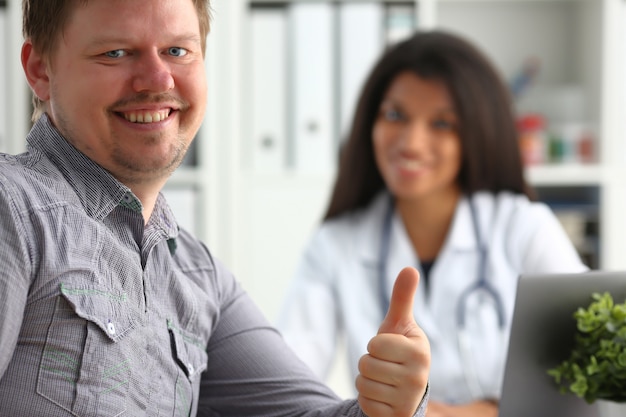 Foto hombre mostrando signo bien con el pulgar hacia arriba en el consultorio del médico