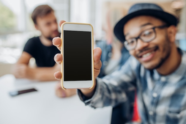 Hombre mostrando smartphone con pantalla vacía