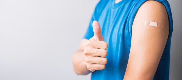 Hombre mostrando su brazo con una venda después de recibir la vacuna